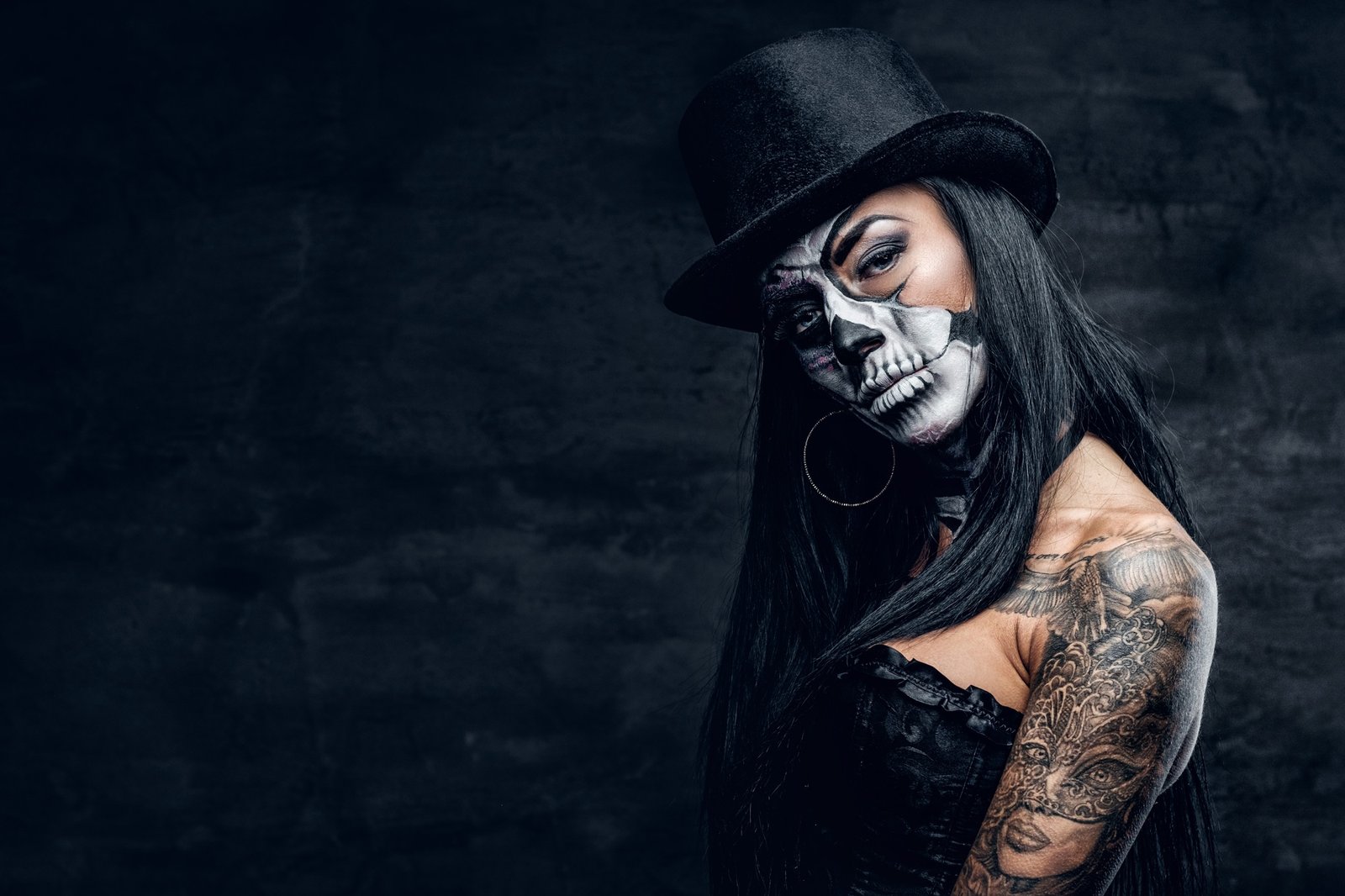 A girl in stylish top hat with skull make up.