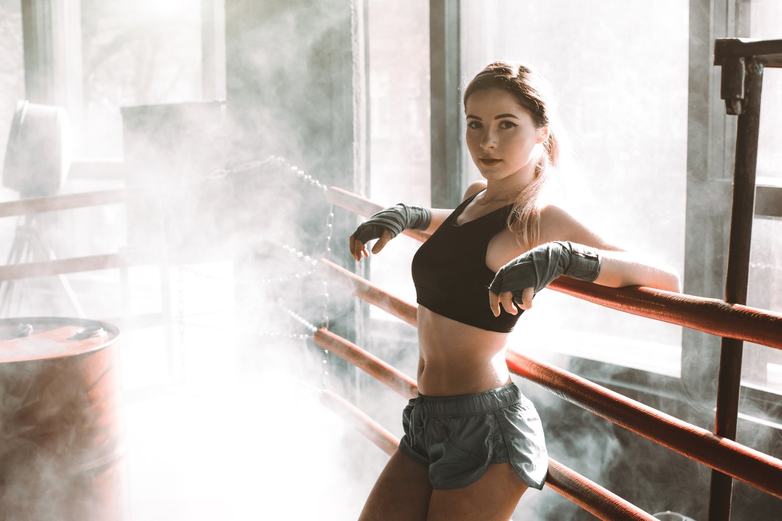 Young pretty woman standing on ring and resting. Close-up portrait of female fit girl at a boxing